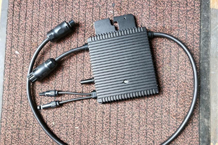 Der Hoymiles HM-350 Balkonkraftwerk Mikrowechselrichter liegt auf einem Teppich samt Verkabelung.